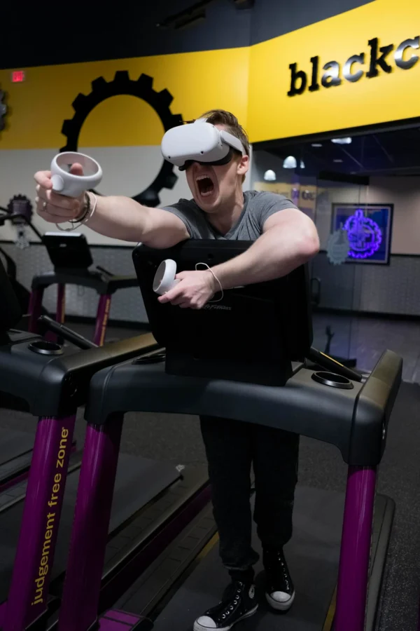 An adult engaging in virtual reality exercise on a treadmill, with VR goggles and controllers.